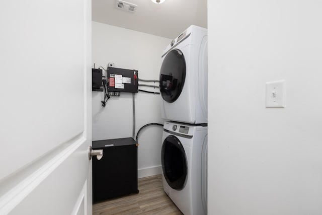 clothes washing area with stacked washer and dryer and light hardwood / wood-style flooring