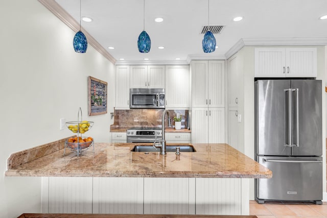 kitchen with white cabinetry, sink, hanging light fixtures, light stone counters, and stainless steel appliances