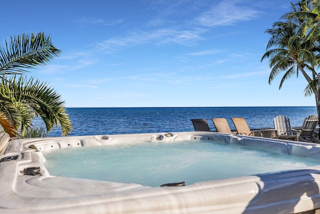 view of swimming pool featuring a hot tub and a water view