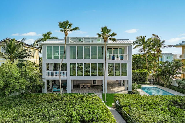 rear view of house featuring a fenced in pool, a balcony, and a patio area