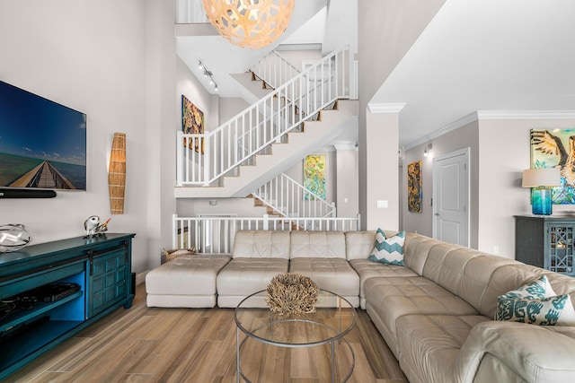 living room featuring hardwood / wood-style flooring, ornamental molding, and a high ceiling