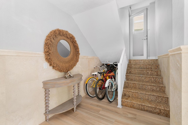 staircase featuring vaulted ceiling, hardwood / wood-style floors, and tile walls