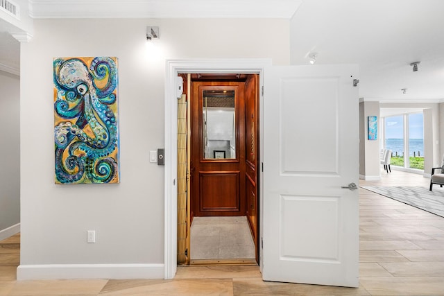 corridor with light hardwood / wood-style flooring, ornamental molding, and a water view