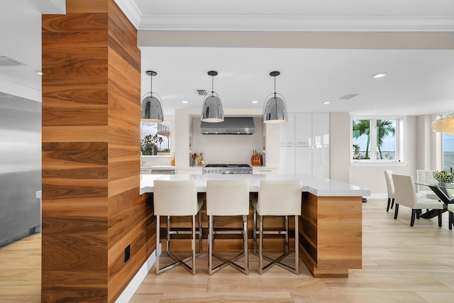 bar with wall chimney range hood, ornamental molding, and pendant lighting