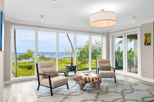 sunroom / solarium featuring a water view and french doors