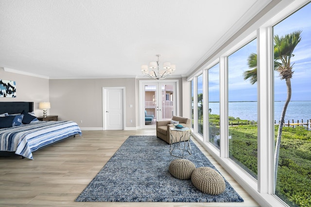 bedroom with a water view, crown molding, an inviting chandelier, light hardwood / wood-style flooring, and a textured ceiling