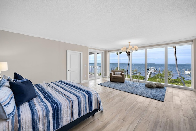 bedroom featuring a water view, ornamental molding, a notable chandelier, access to exterior, and light hardwood / wood-style floors