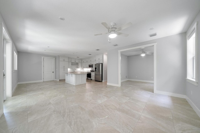 unfurnished living room with a wealth of natural light and ceiling fan