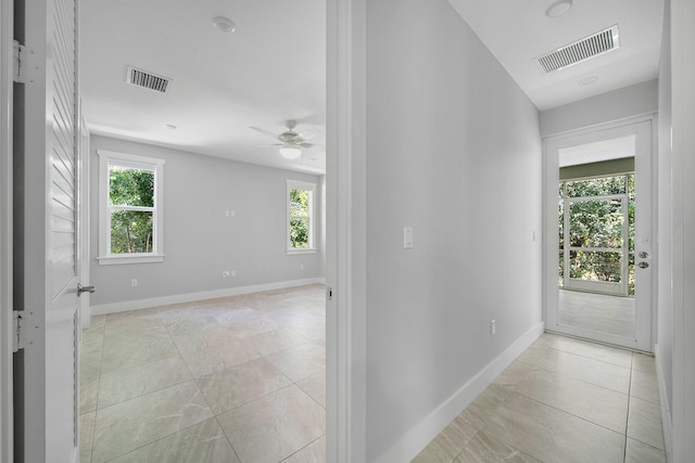 hallway featuring light tile patterned flooring and a healthy amount of sunlight