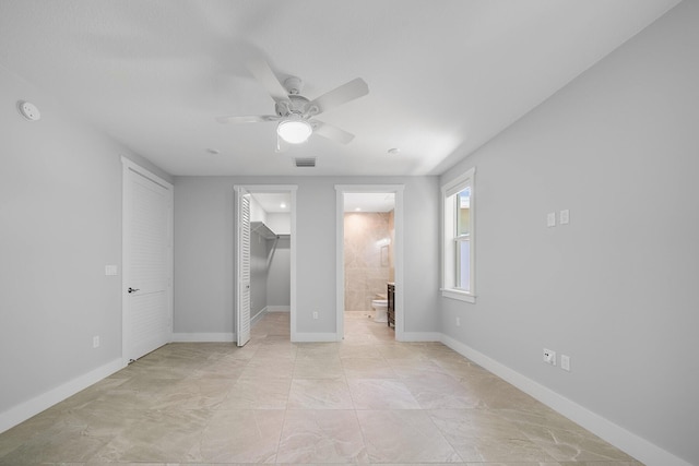 unfurnished bedroom featuring a spacious closet, connected bathroom, ceiling fan, and a closet