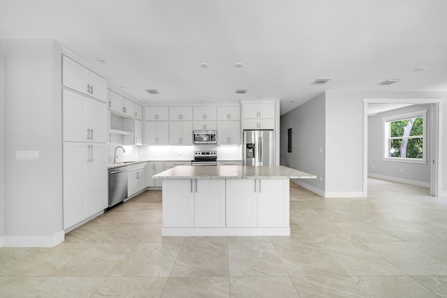 kitchen featuring a kitchen island, white cabinetry, appliances with stainless steel finishes, and sink