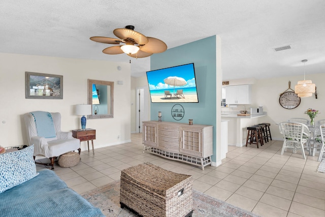 living room featuring light tile patterned floors, a textured ceiling, and ceiling fan