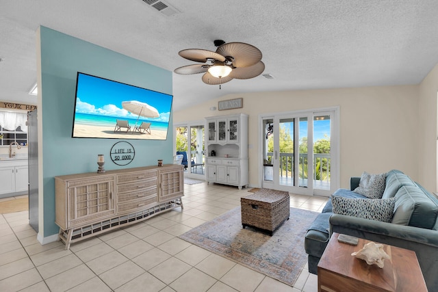 living room with light tile patterned flooring, lofted ceiling, sink, and a textured ceiling