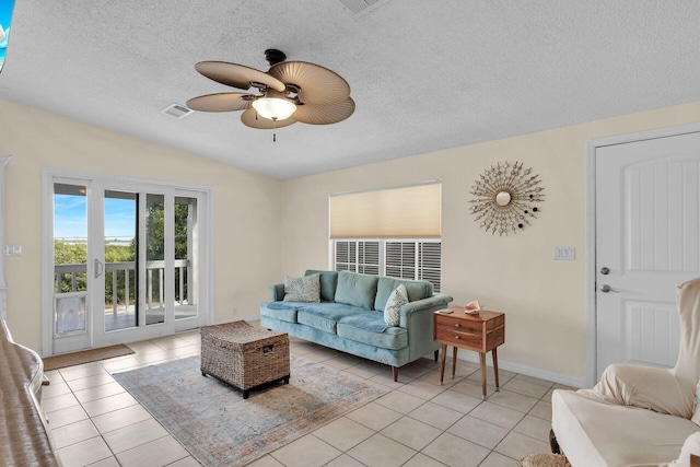 living room featuring ceiling fan, a textured ceiling, and light tile patterned floors