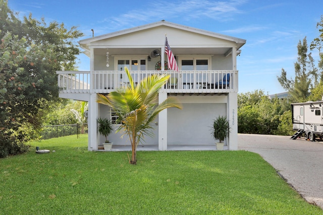 coastal home featuring a balcony and a front yard