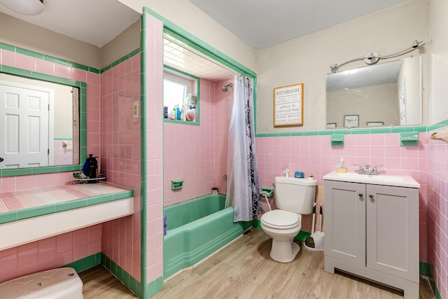 full bath with shower / tub combo, tile walls, toilet, and wood finished floors