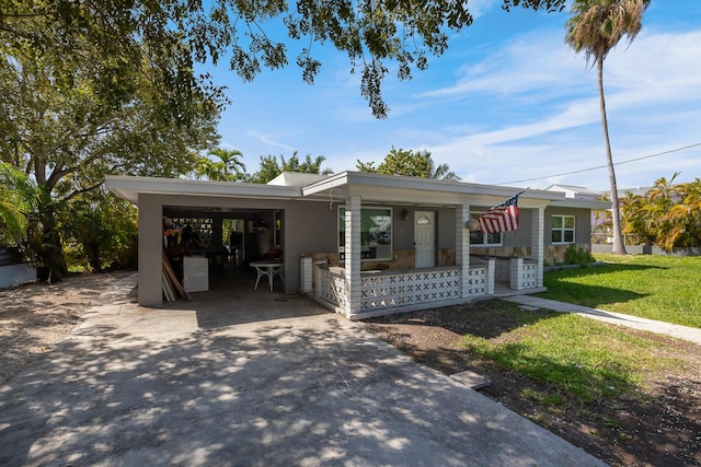 view of front of property with covered porch, a front lawn, a carport, and concrete driveway