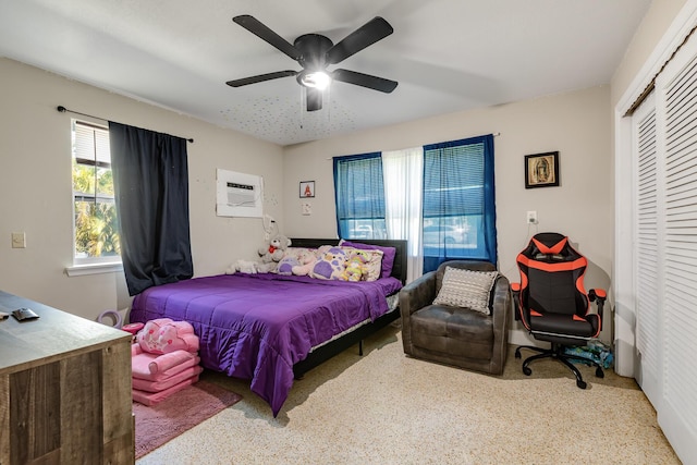 bedroom with a wall unit AC, a ceiling fan, and a closet