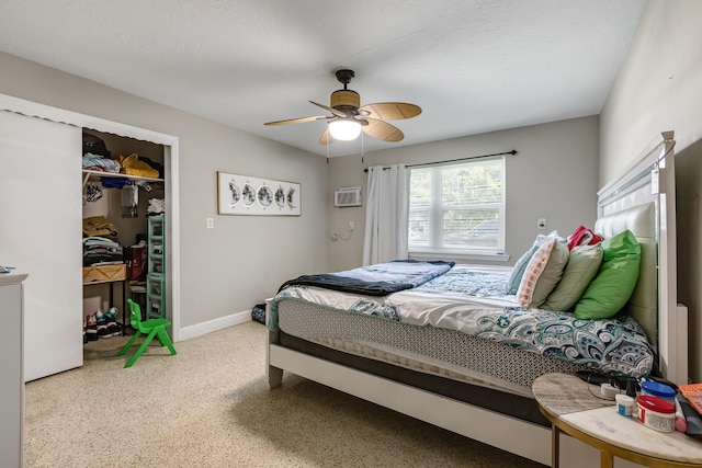 bedroom featuring ceiling fan, a wall unit AC, speckled floor, baseboards, and a closet