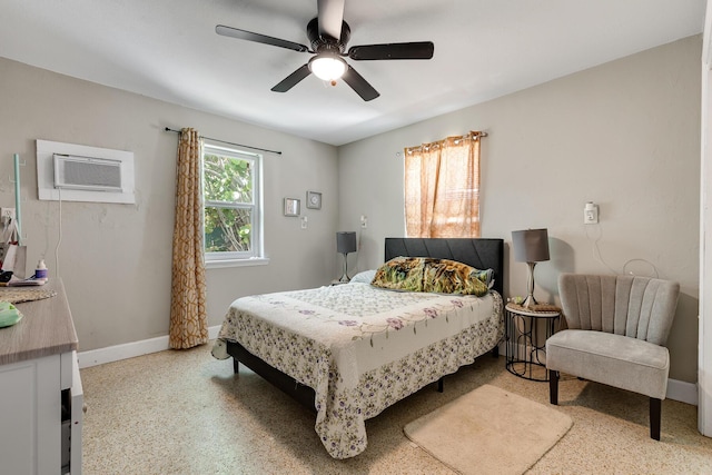 bedroom with a ceiling fan, an AC wall unit, baseboards, and speckled floor