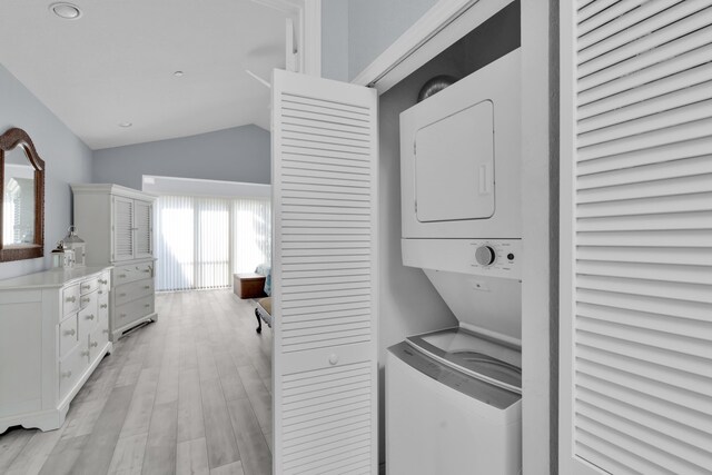 laundry room featuring stacked washer and dryer and light wood-type flooring