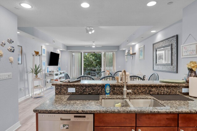 kitchen with stainless steel dishwasher, light stone countertops, sink, and light hardwood / wood-style flooring