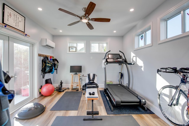 exercise room with hardwood / wood-style floors, a wall mounted AC, and ceiling fan