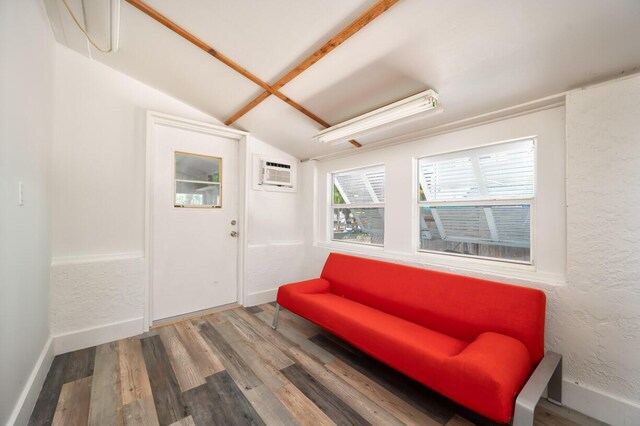 sitting room featuring hardwood / wood-style flooring, a wall mounted air conditioner, and vaulted ceiling