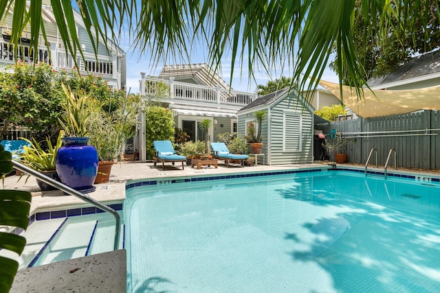 community pool featuring a storage shed, a patio, an outdoor structure, and fence