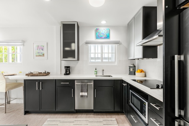 kitchen with light countertops, wall chimney exhaust hood, glass insert cabinets, and stainless steel appliances