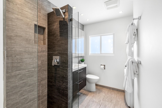 bathroom with baseboards, a tile shower, visible vents, and toilet