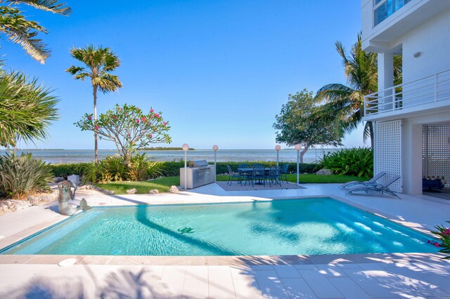 view of swimming pool featuring a water view and a patio area