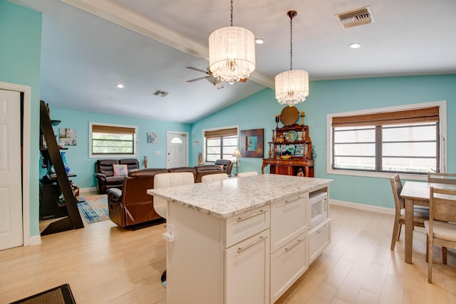 kitchen featuring hanging light fixtures, a kitchen island, white cabinets, and light wood-type flooring