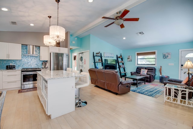 kitchen with wall chimney exhaust hood, white cabinetry, a center island, hanging light fixtures, and stainless steel appliances