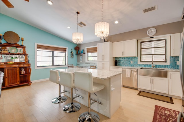 kitchen featuring a kitchen island, decorative light fixtures, sink, white cabinets, and stainless steel dishwasher