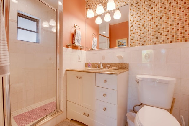 bathroom with vanity, toilet, a shower with shower door, and tile walls