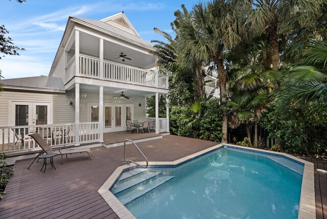 view of swimming pool with a wooden deck, french doors, and ceiling fan