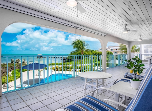 view of patio featuring ceiling fan, a community pool, a balcony, and a water view