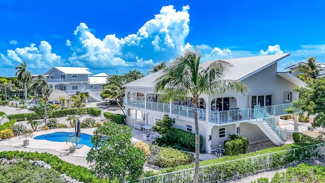 back of property featuring a fenced in pool, a patio, and a balcony