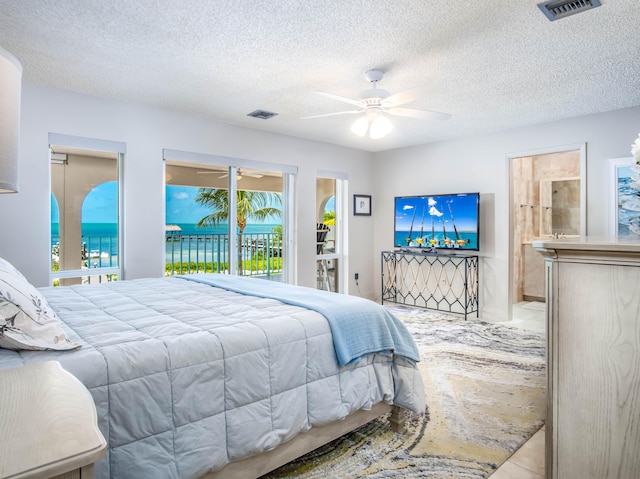 bedroom featuring access to exterior, ensuite bathroom, a textured ceiling, and ceiling fan