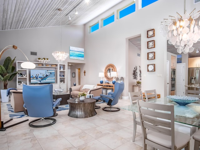 living room featuring a notable chandelier, track lighting, built in features, and a high ceiling