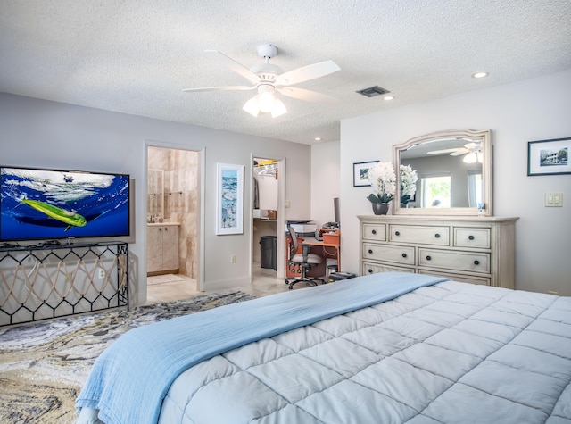 bedroom featuring ceiling fan, a spacious closet, ensuite bathroom, and a textured ceiling