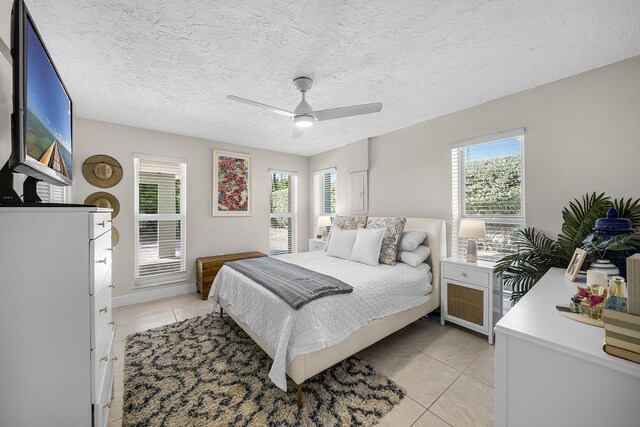 bedroom featuring ceiling fan, multiple windows, and light tile patterned floors