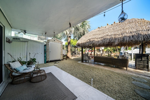 view of patio featuring a gazebo, ceiling fan, an outdoor living space, and a shed