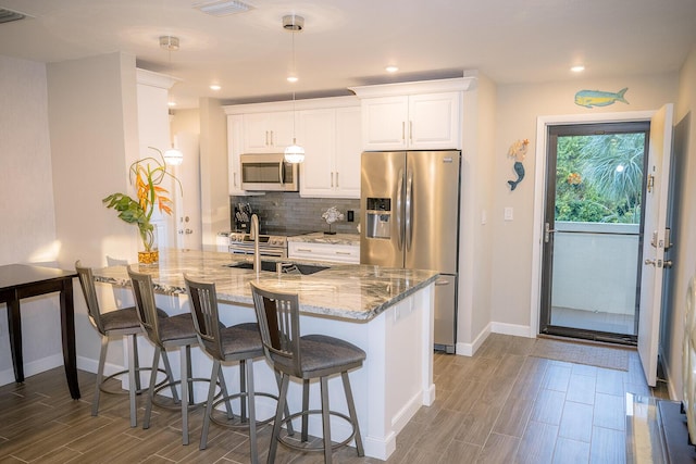 kitchen with tasteful backsplash, white cabinetry, appliances with stainless steel finishes, and light stone counters