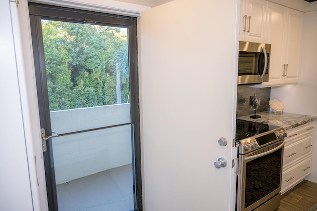 kitchen with light stone counters, plenty of natural light, stainless steel appliances, and white cabinets