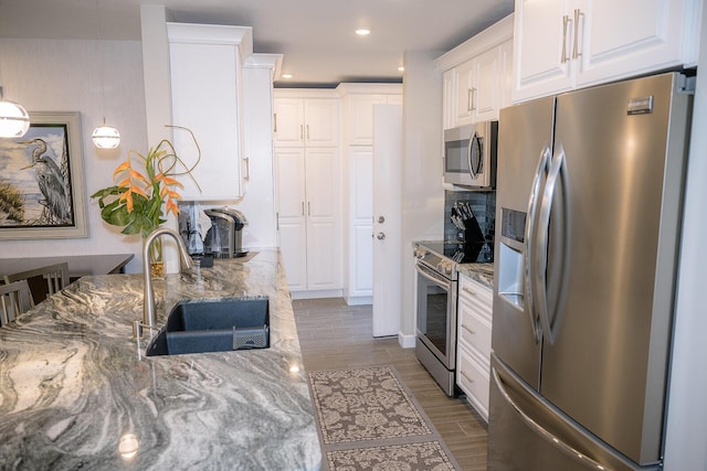 kitchen with sink, stone counters, white cabinets, and appliances with stainless steel finishes