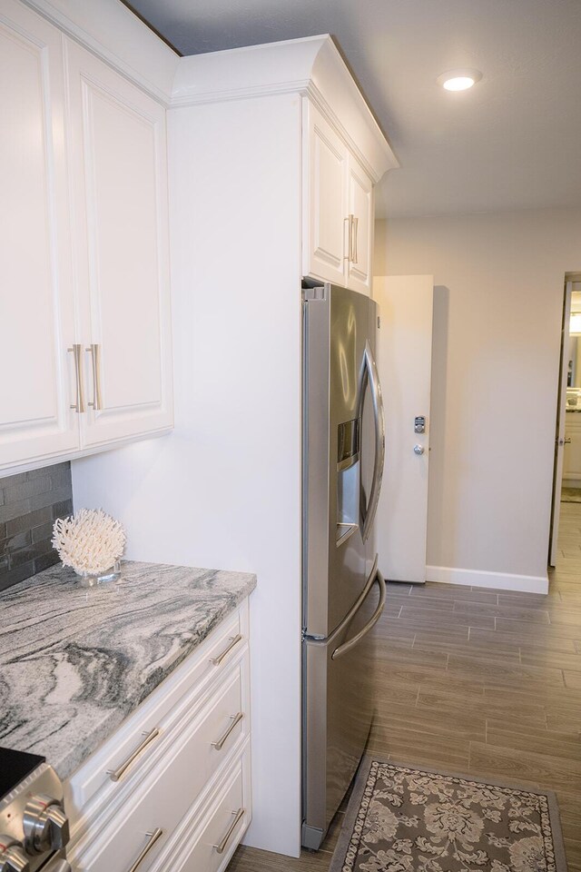 kitchen featuring light stone counters, stainless steel fridge with ice dispenser, dark wood-type flooring, and white cabinets