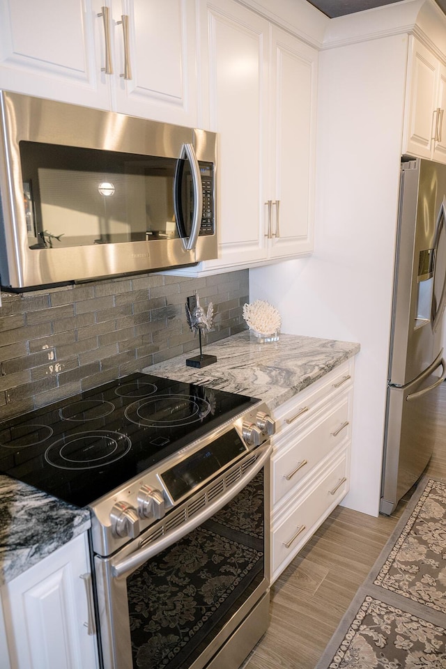 kitchen featuring light stone counters, appliances with stainless steel finishes, light hardwood / wood-style floors, decorative backsplash, and white cabinets