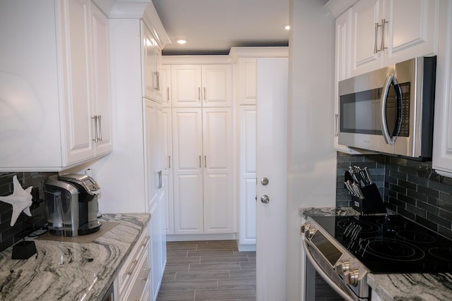 kitchen featuring white cabinetry, light stone counters, decorative backsplash, and appliances with stainless steel finishes